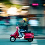 photo of man riding red motor scooter