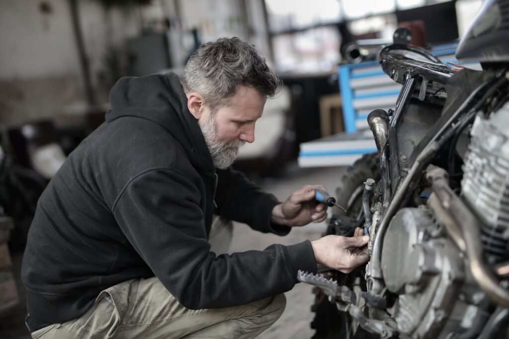 bearded man fixing motorcycle in workshop