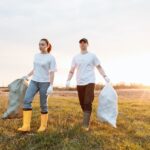 a man and a woman holding sacks of garbage